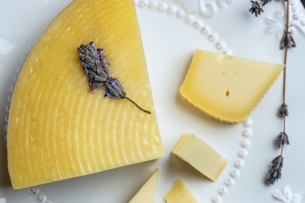 Stuk lavendelkaas met droge lavendelbloemen in plaat op grijze tafel, ecologie en eco-producten.