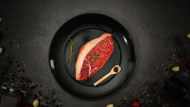 Stuk rauw vers vlees Picanha steak op stenen tafel met zeezout en rozemarijn en specerijen