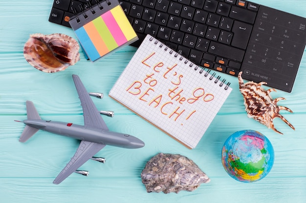 Stuk speelgoed vliegtuig met bol, schelpen en toetsenbord op blauwe kleurenachtergrond. Concept reizen en vakantie naar het strand.