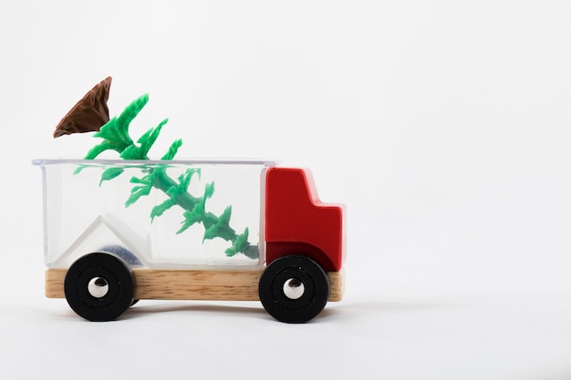 Foto stuk speelgoed vrachtwagen en plastic kerstboom op een witte achtergrond. detailopname