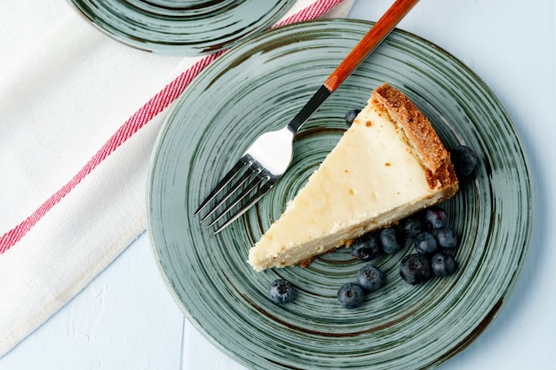 Stuk van klassieke cheesecake op groene plaat