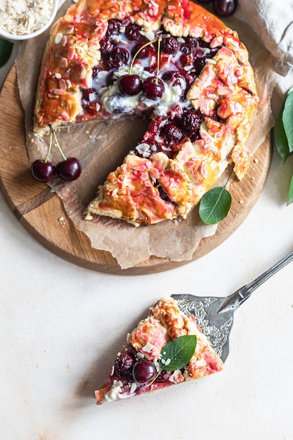 Stuk van open taart of galette met kersen-, amandel- en vanille-ijs, lichte achtergrond. Bovenaanzicht.