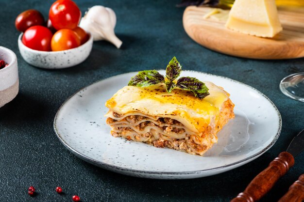 Stuk van smakelijke warme lasagne op donkere achtergrond. Traditionele Italiaanse lasagne. Italiaans eten. Lasagne sluiten. Bolognese saus. Bechamelsaus. Stilleven van voedsel. Huisgemaakte vleeslasagne.