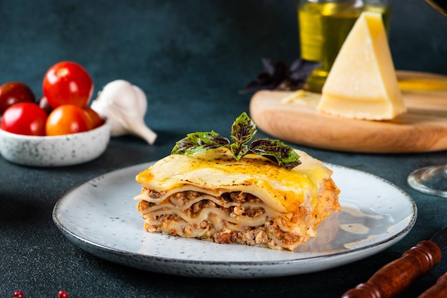 Stuk van smakelijke warme lasagne op donkere achtergrond. traditionele italiaanse lasagne. italiaans eten. lasagne sluiten. bolognese saus. bechamelsaus. stilleven van voedsel. huisgemaakte vleeslasagne.