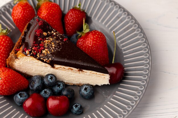 Stukje cheesecake met chocolade top en bessen