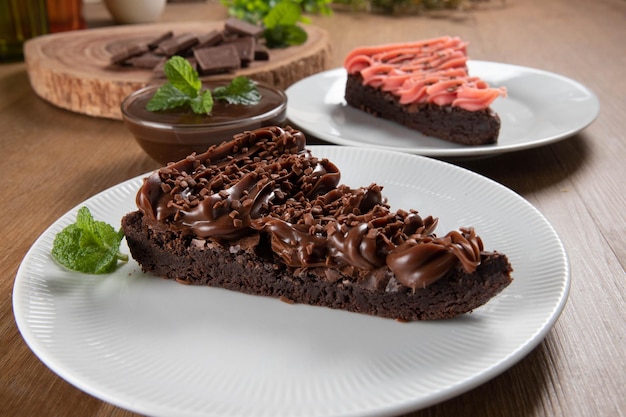 Stukje Chocolade Brownie Slice met Aardbeien en Chocolade Icing Houten tafel met munt en chocoladeschilfers op de achtergrond
