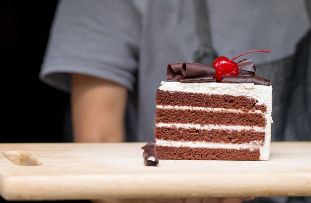 Stukje chocoladetaart met vanille glazuur en kersengelei.