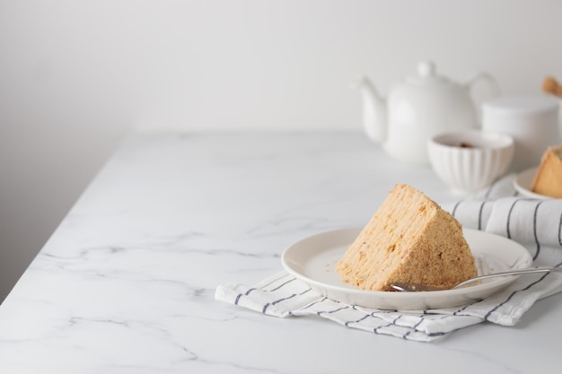 Stukje gelaagde zelfgemaakte honingcake op de witte tafel