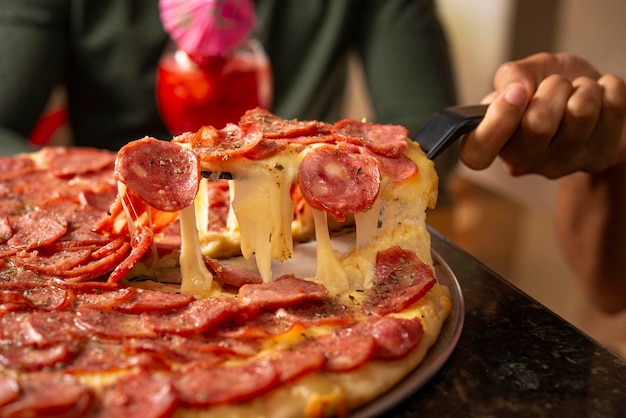 Foto stukje salami pizza wordt getrokken en kaas wordt uitgerekt