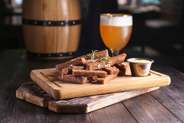 Stukjes brood met kruiden en saus op houten plank