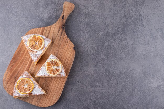 Stukjes cake met gedroogde plakjes citroen op stenen tafel.