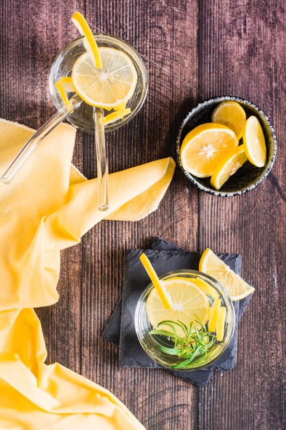 Stukjes citroen in een glas water en rozemarijn op tafel Detox drankje Bovenaanzicht en verticaal zicht