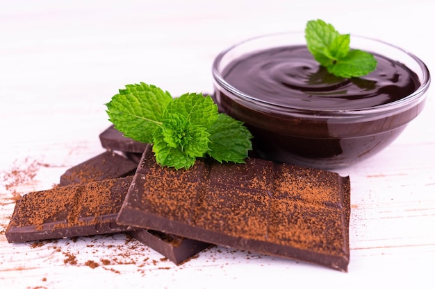 Stukjes donkere chocolade en chocolade in een bord, bestrooid met cacao op een houten ondergrond