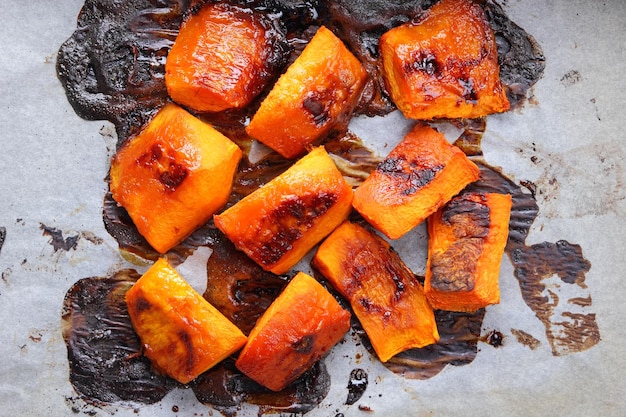 Stukjes gebakken pompoen op perkament Gebakken pompoen op een bakplaat Herfst vegetarisch dessert van groenten Bovenaanzicht