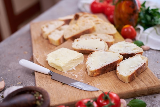 Stukjes gesneden stokbrood met smeerboter op houten plank