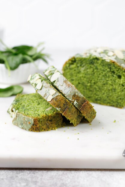 Stukjes groene sponscake met spinazie Groene taart met geschaafde amandelen gesneden op marmeren bord