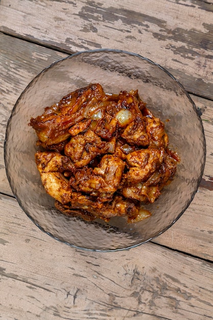 Stukjes kip in saus in een glasplaat op een houten tafel