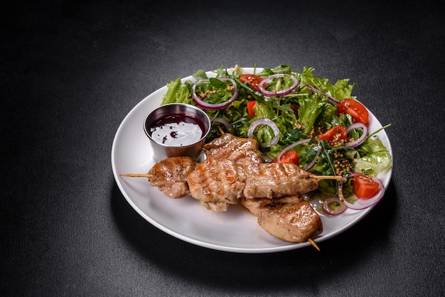 Stukjes kipfilet gebakken op gegrilde houten stokjes met salade en rode saus. Voorbereiding van de feesttafel