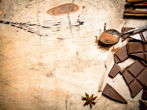 Stukjes melkchocolade met cacao en kaneel op houten achtergrond