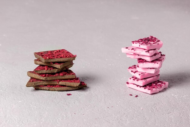 Stukjes modieuze roze en melkchocolade met stukjes bessen en fruit liggen er bovenop