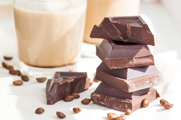 Stukjes pure chocolade, koffiebonen en kopjes cacao of koffie met melk.
