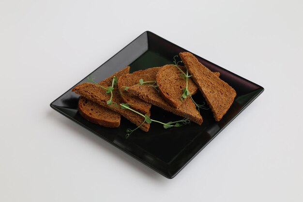Stukjes roggebrood op een zwart bord op een witte achtergrond