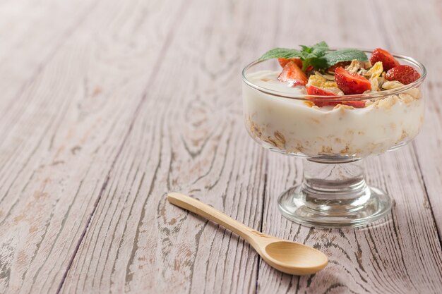 Stukjes verse aardbeien in yoghurt met munt op een houten tafel. Heerlijke, gezonde en voedzame natuurvoeding.