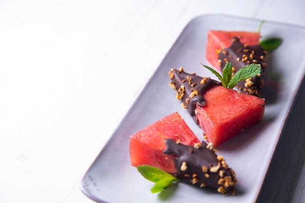 Stukjes verse watermeloen gedoopt in chocolade en omhuld met gekarameliseerde amandelen.