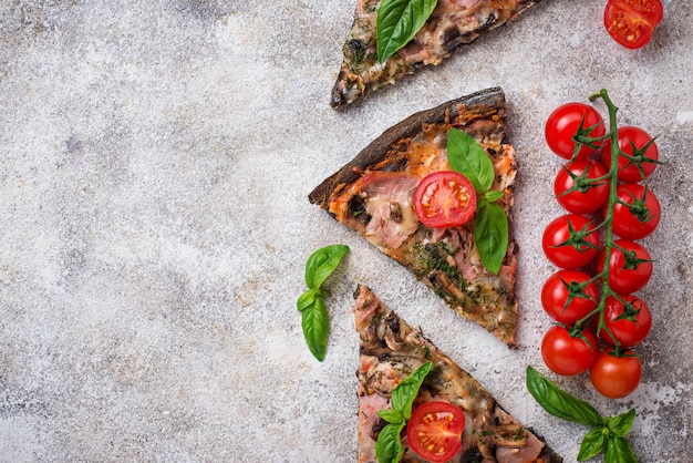 Stukjes zwarte pizza met tomaten en basilicum