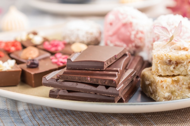 Stukken eigengemaakte chocolade met kokosnotensuikergoed op een blauw en bruin textiel. zijaanzicht