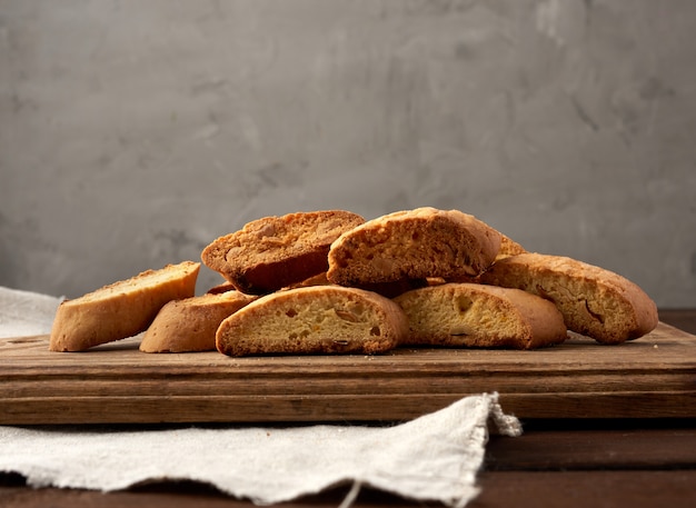 Stukken gebakken Italiaanse biscottikoekjes op een bruine houten raad