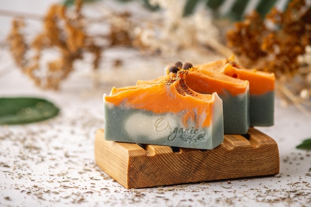 Stukken heldere natuurlijke handgemaakte zeep op een houten zeepbakje met groene bladeren eromheen