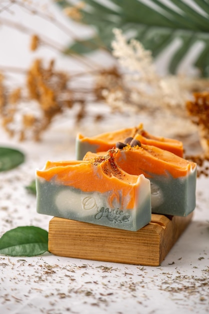 Stukken heldere natuurlijke handgemaakte zeep op een houten zeepbakje met groene bladeren eromheen