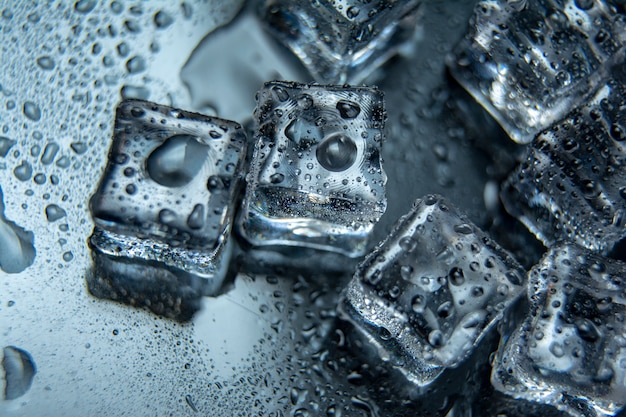 Stukken ijsblokjes met waterdruppels op zwart-mirrowachtergrond.