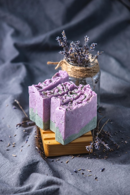 Foto stukken natuurlijke lavendel handgemaakte zeep op een houten zeepbak en op een donkere stof achtergrond