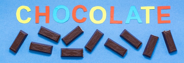 Stukken van chocolade en de inscriptie chocolade op een blauwe achtergrond