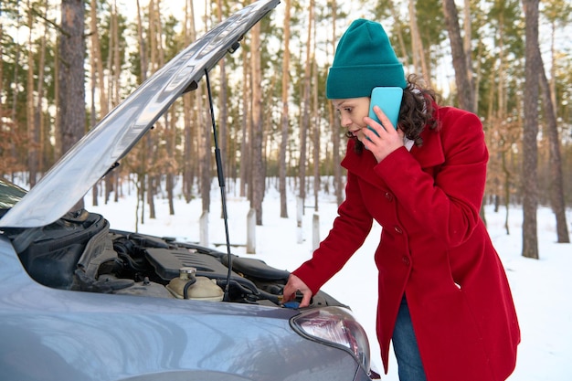 Stunned middle age Caucasian woman trying to fix car breakdown or engine failure and waiting for towing service for help car accident on the road Roadside assistance concept Car troubles concept