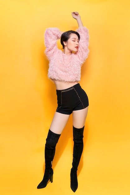 Stunning cute girl posing with pleasure on yellow background. Indoor photo of dancing young lady in trendy fur coat to camera.