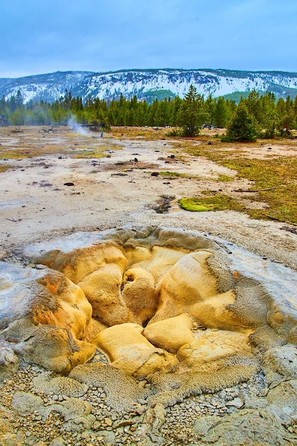 Stunning geyser opening in Yellowstone surrounded by winter hills