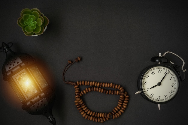 A stunning Ramadan candle lantern and rosary beads with a copy space on black background