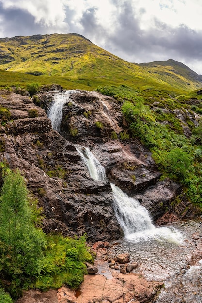 Stunning scenery with high mountains and three waterfalls converging in the Glencoe Valley Scotland
