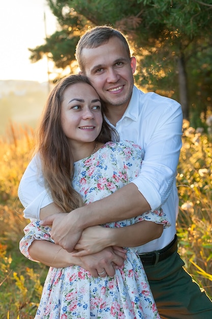 Stunning sensual outdoor portrait of young stylish fashion couple kissing in summer in corn field behind rainy clouds and storm.