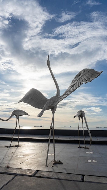 Stunning swan statue standing tall with picturesque blue sky and sea featuring multiple boats