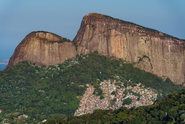 사진 로치나 파벨라 (rocinha favela) 는 남아메리카에서 가장 큰 바위인 도이스 이르마오스 (dois irmaos) 의 경이로운 전망이다.