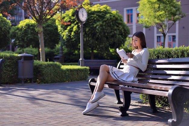 Stunning young lady captivated by book on a bench Tranquil reading haven in city park