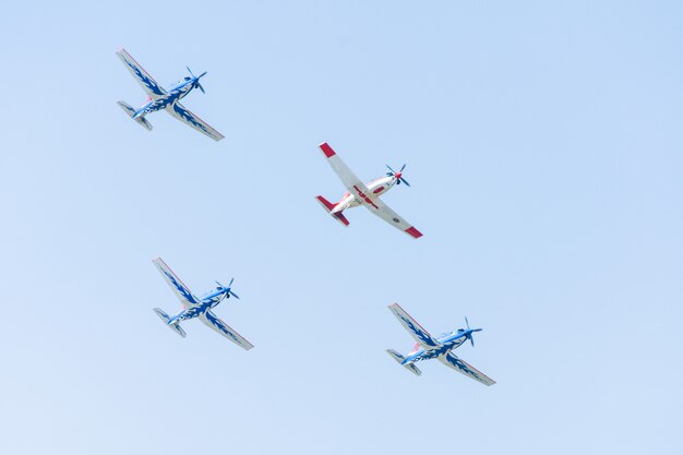 航空ショーのパフォーマンスで明るい青い空を背景に編隊飛行するスタント航空機