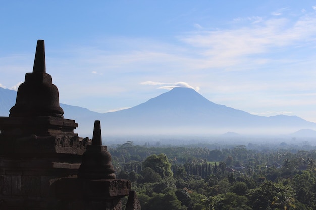 Stupas in de borobudur-tempel tegen de bergen en de lucht op een zonnige dag