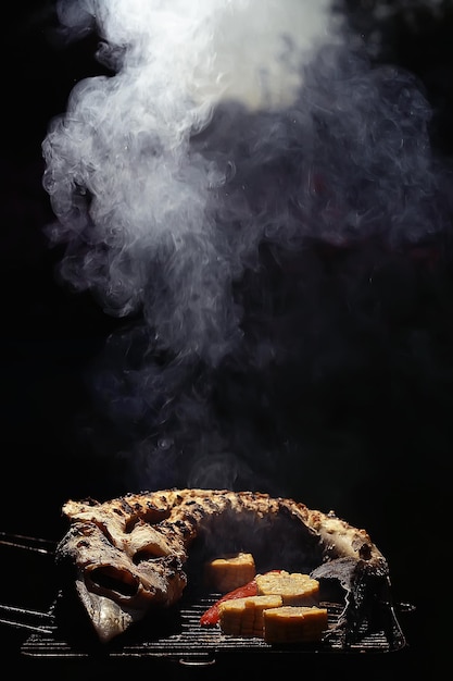 Foto griglia di storione / pesce di storione grande cotto alla griglia, sulla brace con fumo, sterlet affumicato