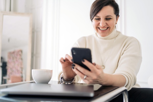 Stuurt een spraakbericht aan de telefoon naar een klant, een stijlvolle vrouwelijke freelancer op kantoor