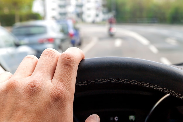 Stuurwiel met stuurprogramma hand op het in moderne auto-interieur met uitzicht op straat